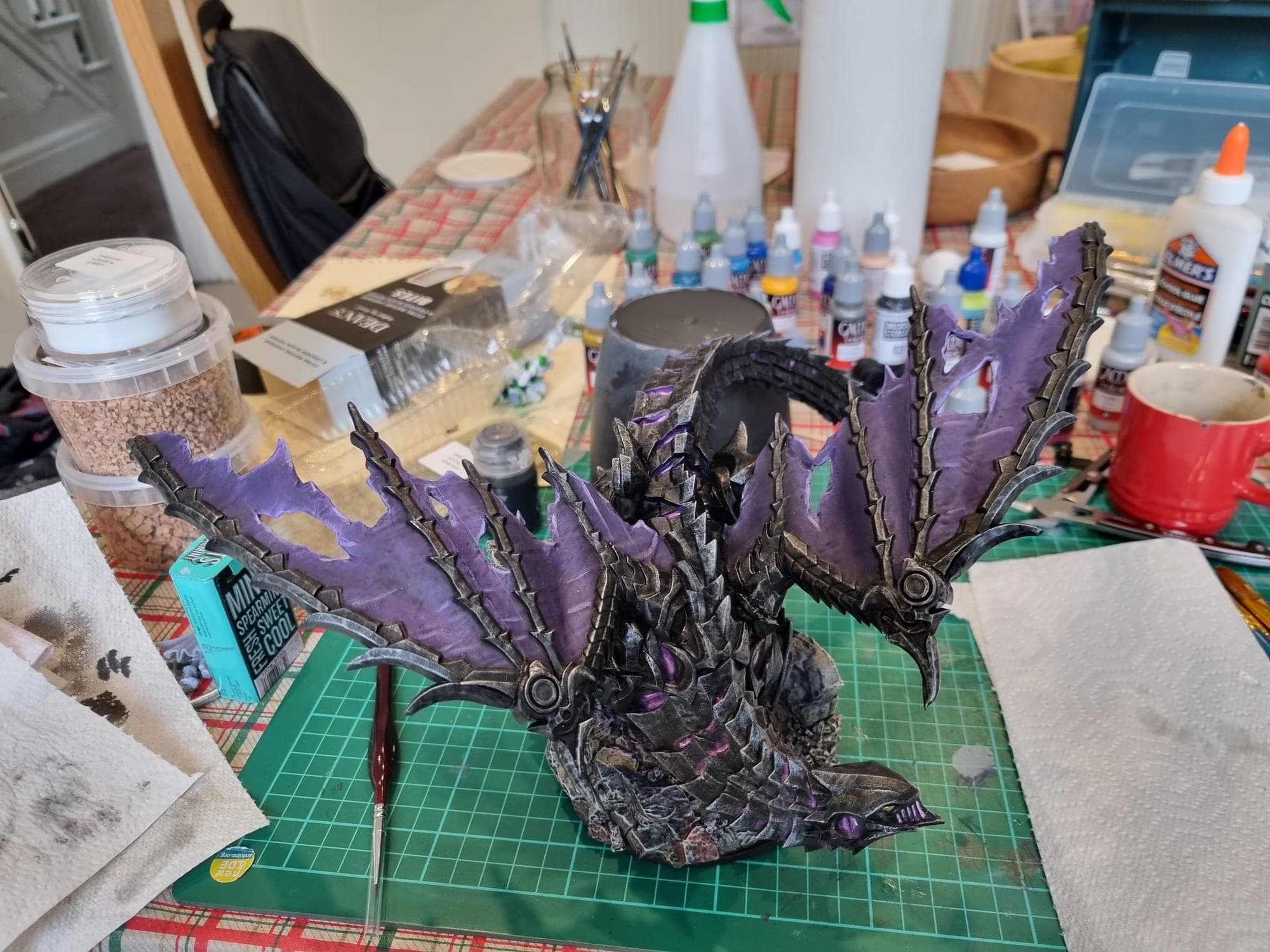 Purple and black dragon with wings spread, finished, on the cutting mat.