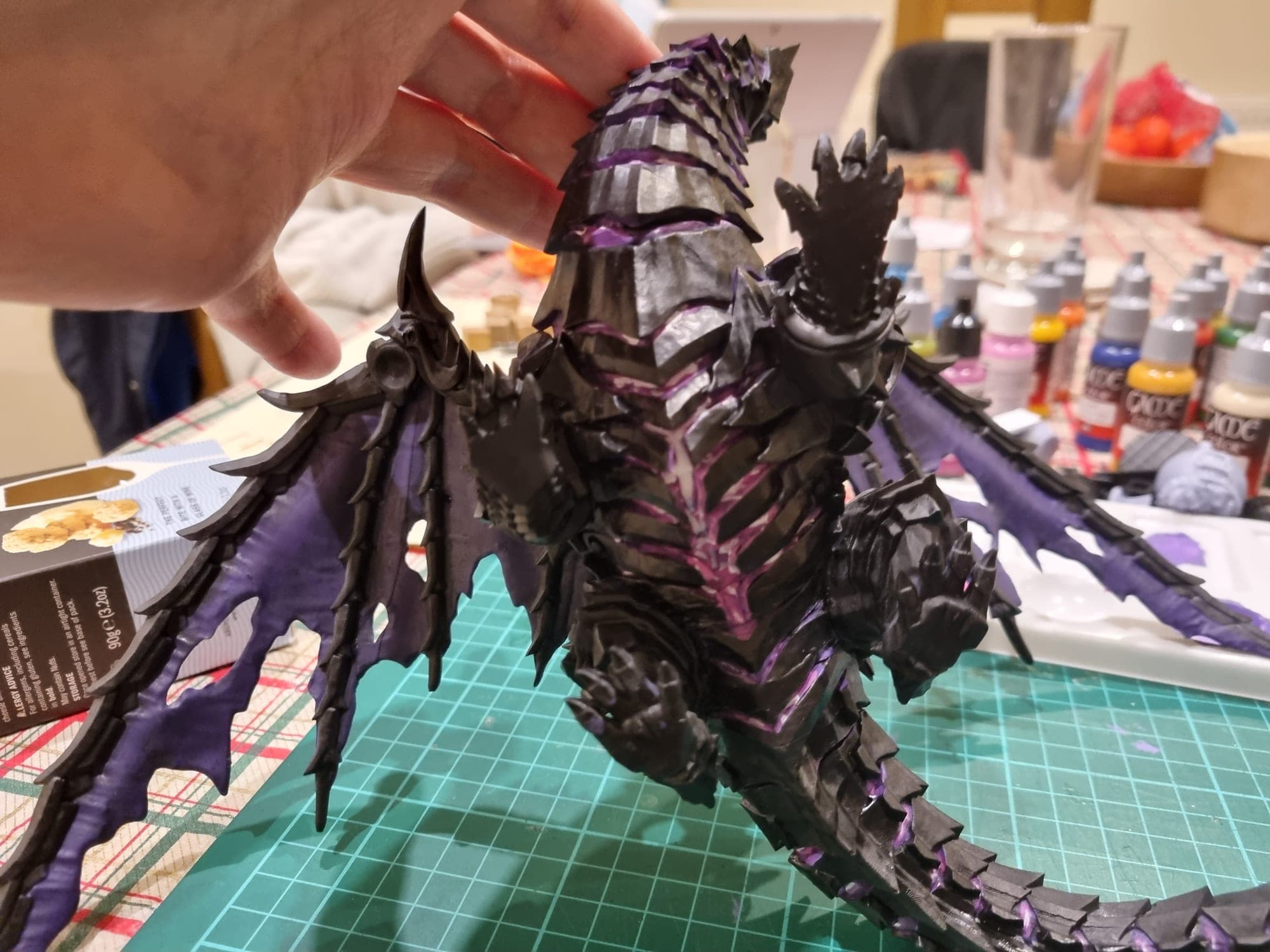 Hand holding the part-painted dragon up to the light.